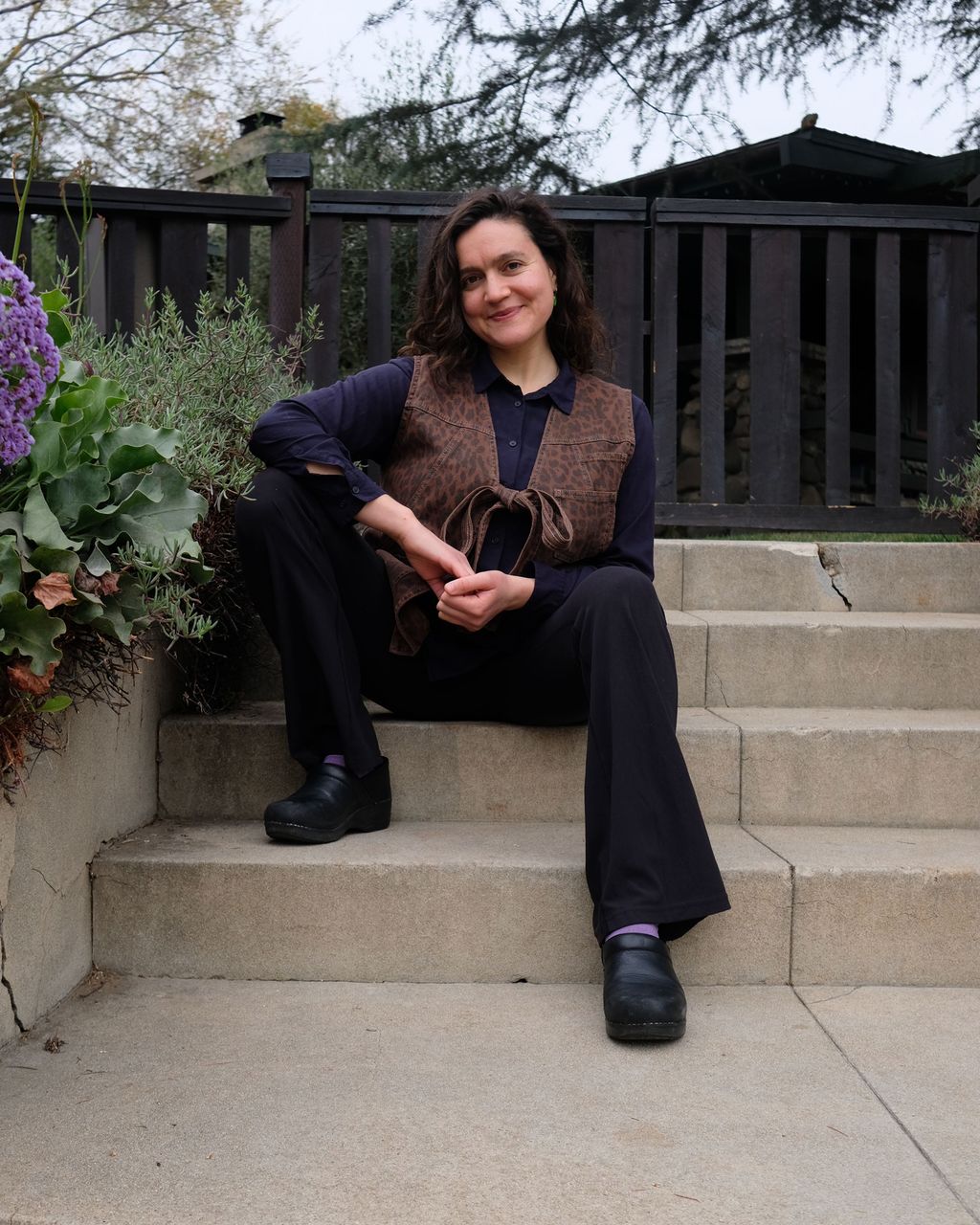 Acupuncturist Callie Ryan sits partway up a small flight of concrete stairs while smiling warmly at the camera
